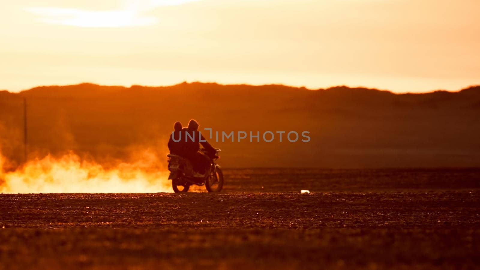 On a motorcycle in the Gobi desert. Dust from under the wheels. Wild Mongolian road.