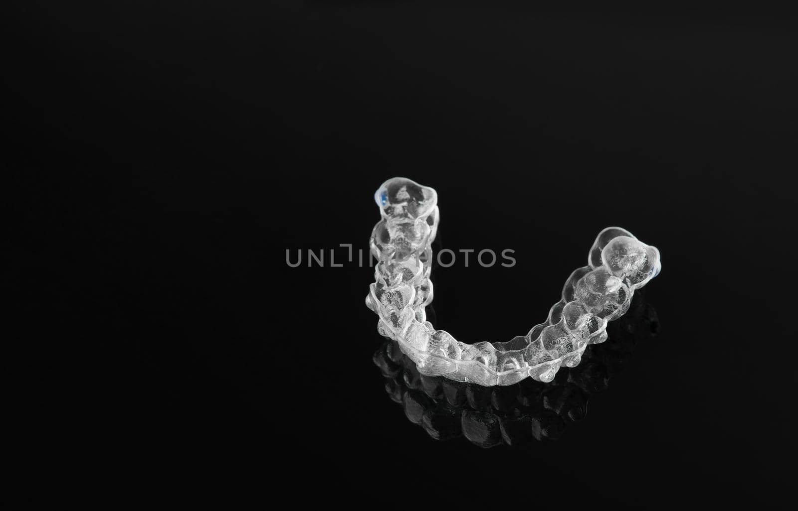 Invisible orthodontics cosmetic brackets on black background, tooth aligners, plastic braces. Modern teeth retainers created on a 3d printer. A way to have a beautiful smile and white teeth.
