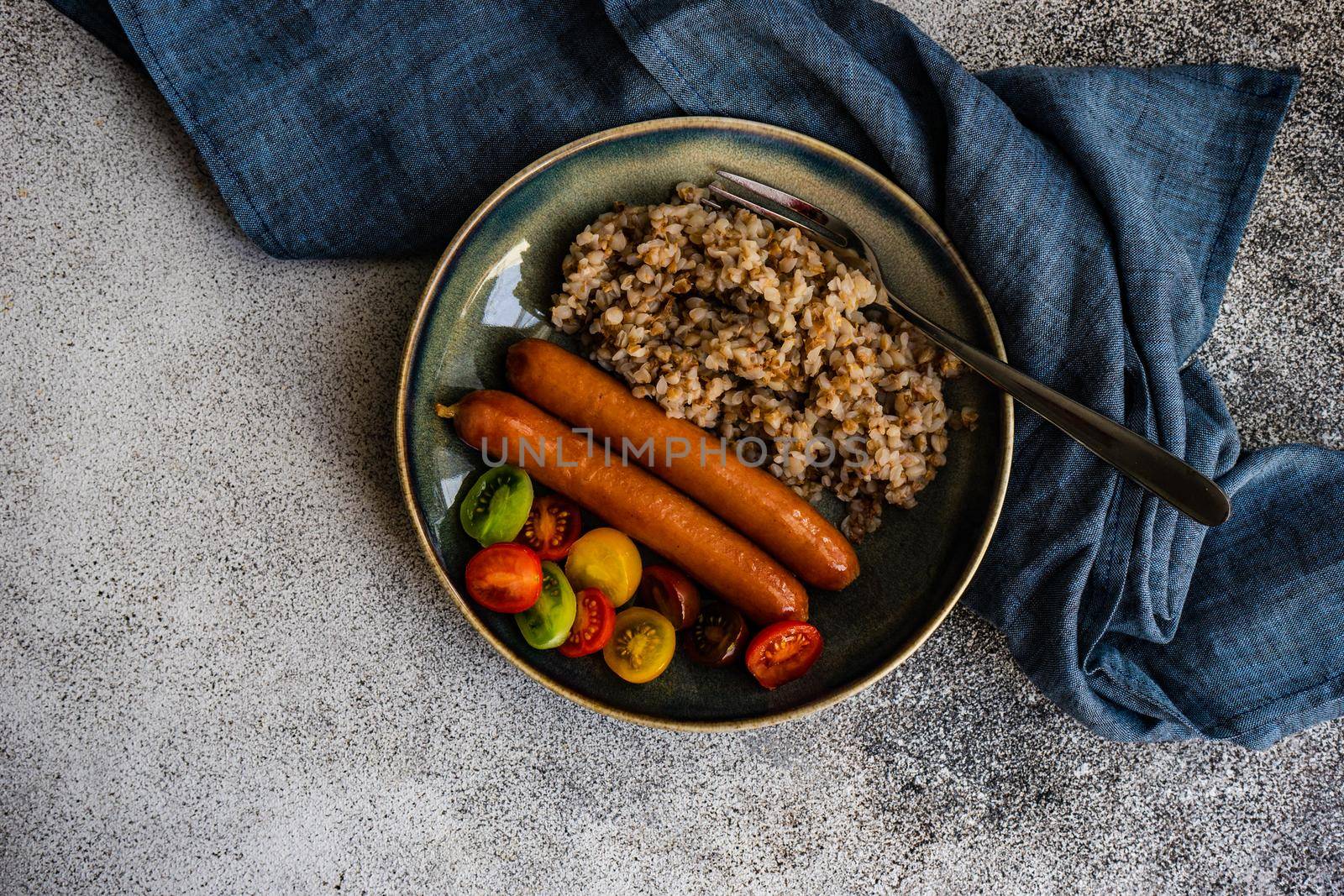 Healthy breakfast with buckwheat, sausages and cherry tomatoes in a bowl
