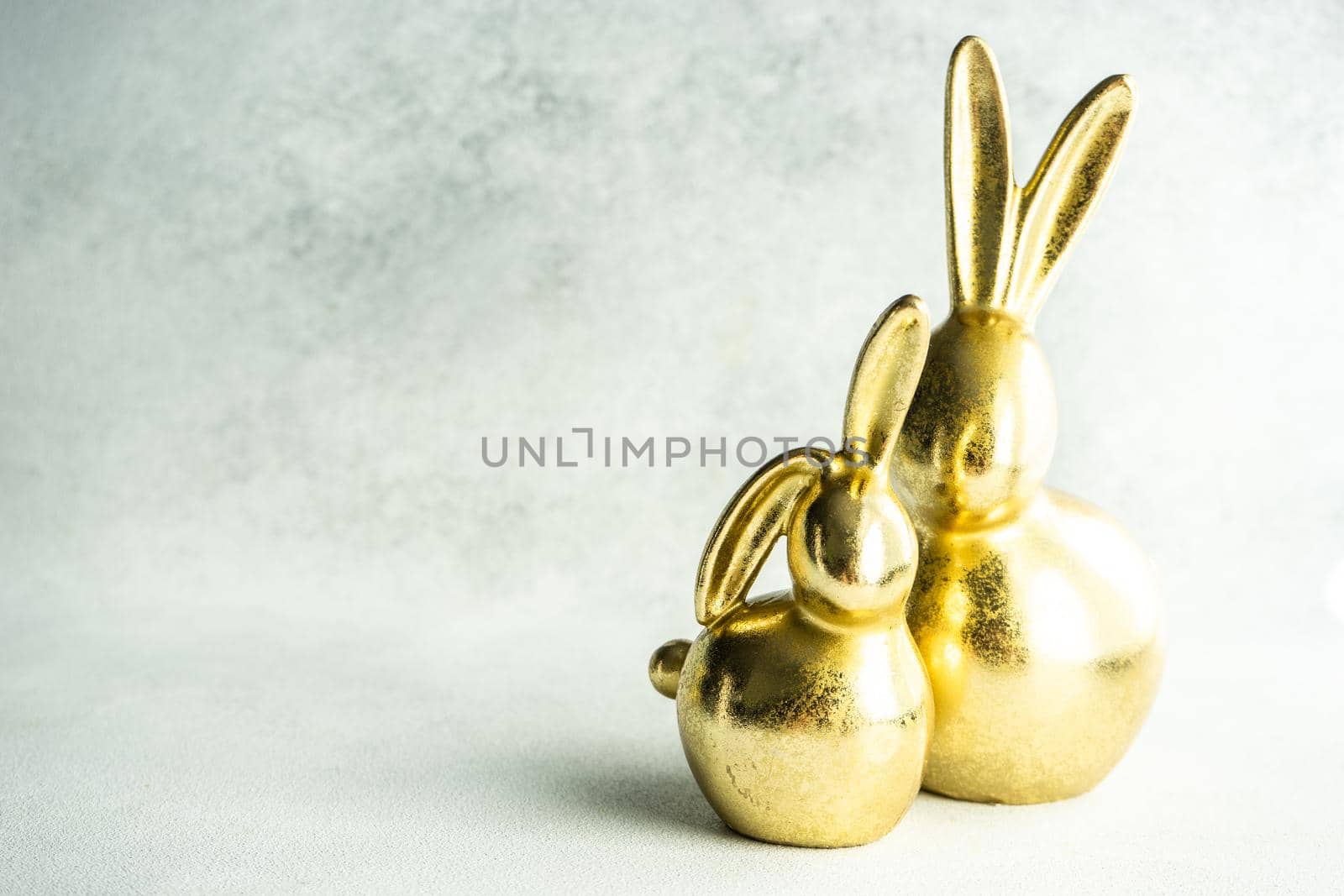 Easter card concept with golden bunnies on concrete background with copy space