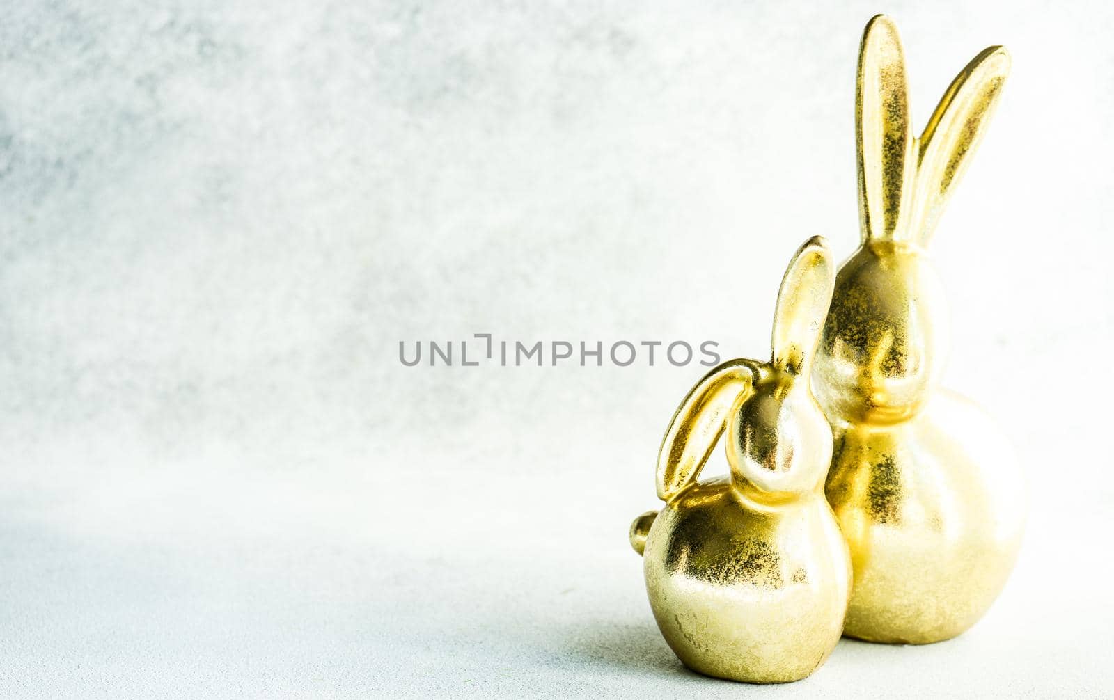 Easter card concept with golden bunnies on concrete background with copy space