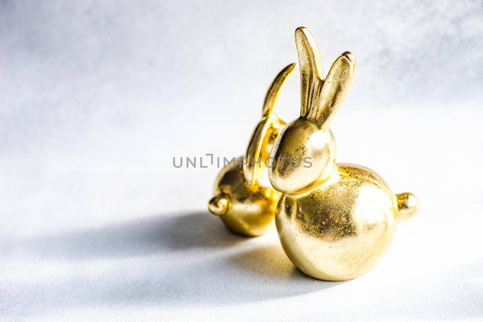 Easter card concept with golden bunnies on concrete background with copy space