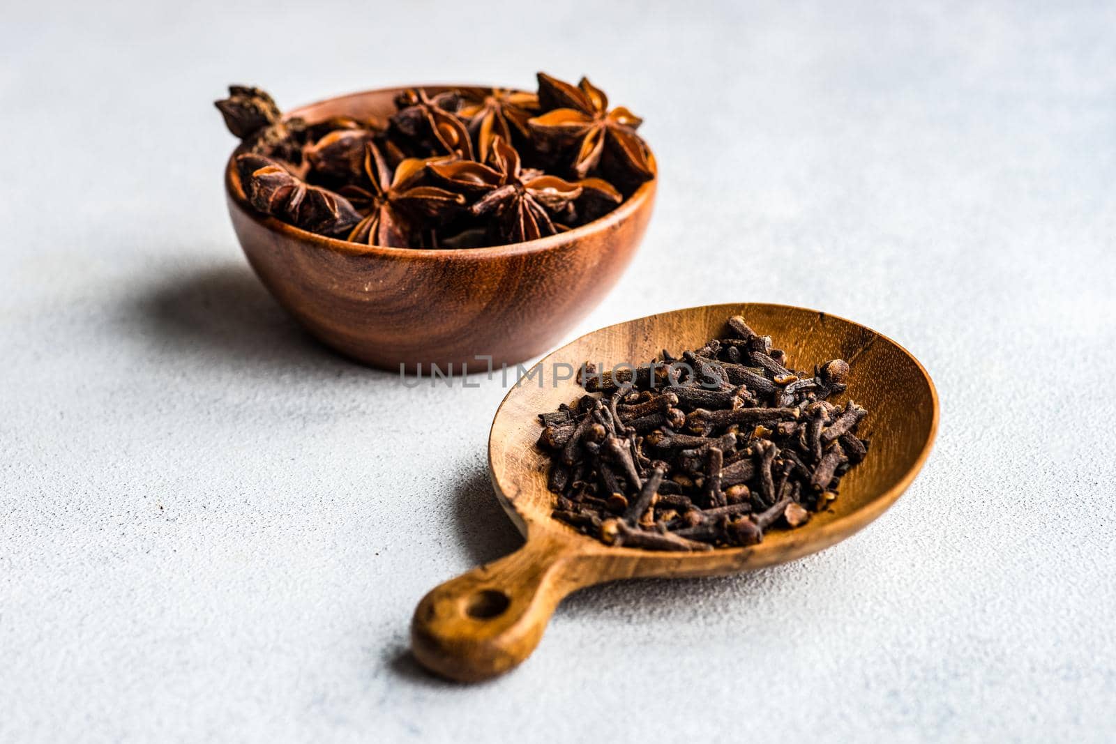 Wooden bowls with organic anise star and cloves on concrete background