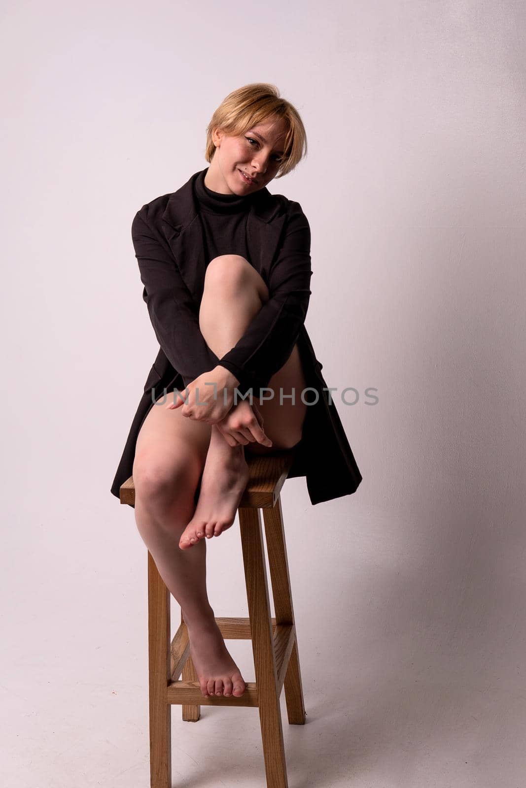 A girl sits on a chair hugging her leg Adult attractive background beautiful breast, In the afternoon care fashion for fit and hygiene lady, purity seductive. Sexy slim wellness, woman