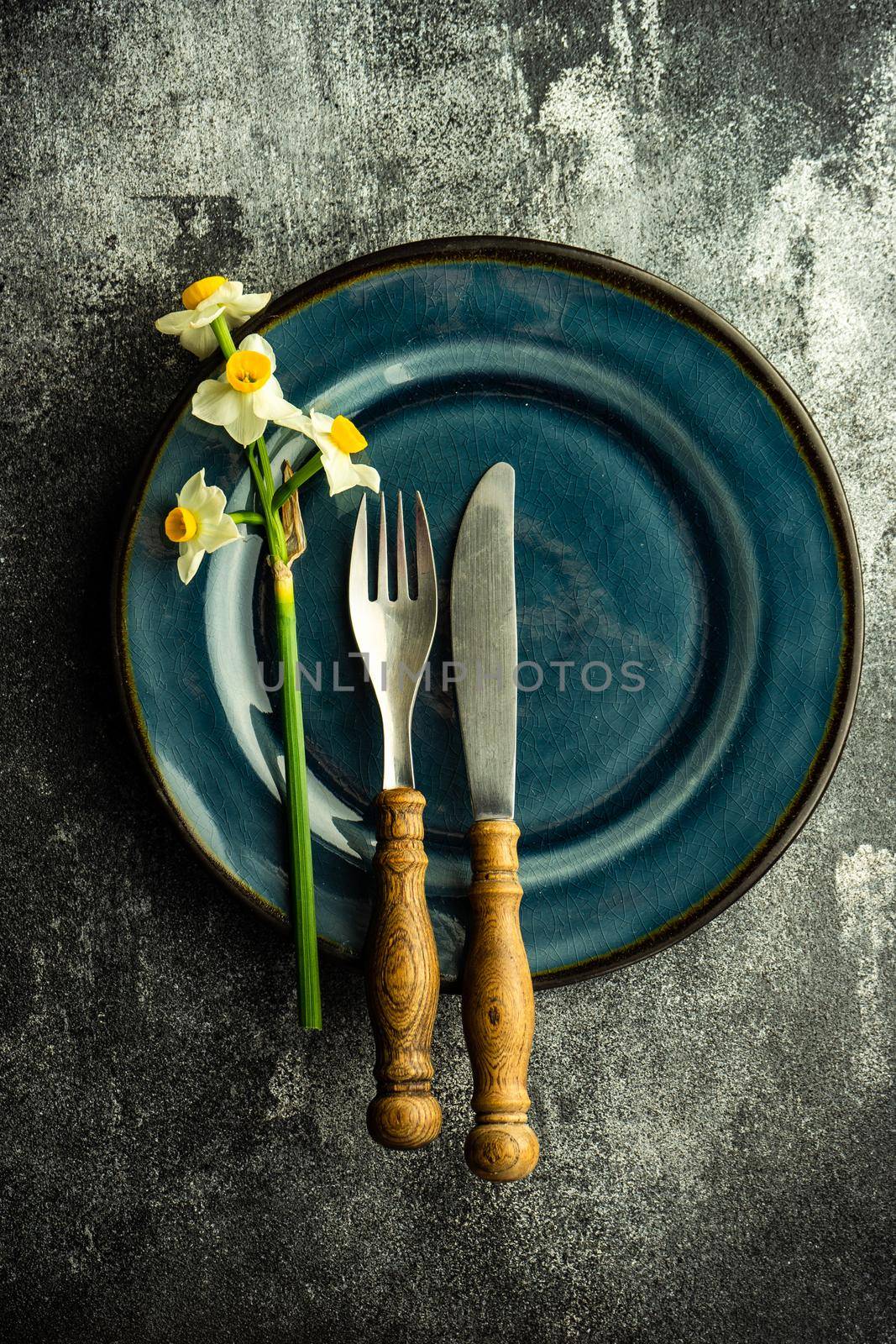 Minimalistic spring table setting decorated with fresh daffodil flowers on concrete background