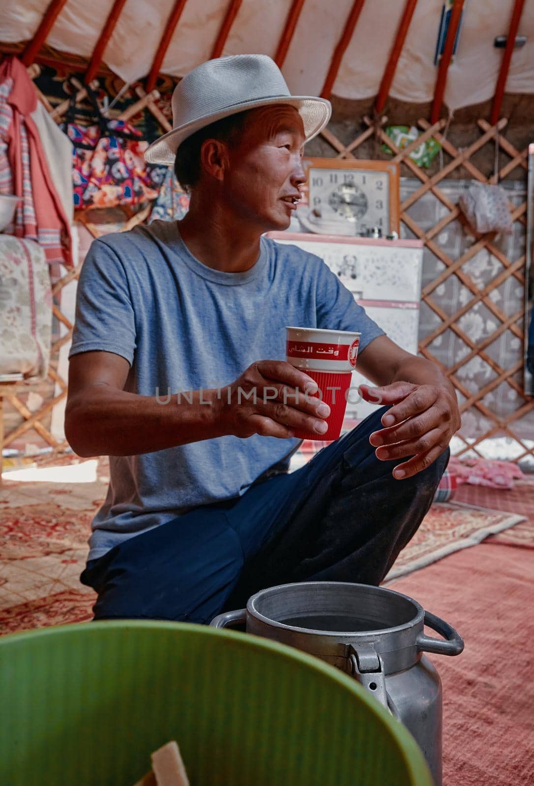 Life of the Mongolian Yurt. Interior of the nomad's house. The man pours some home brew, tasting of home-made alcohol. 06.09.2019. Gobi Desert, Mongolia.