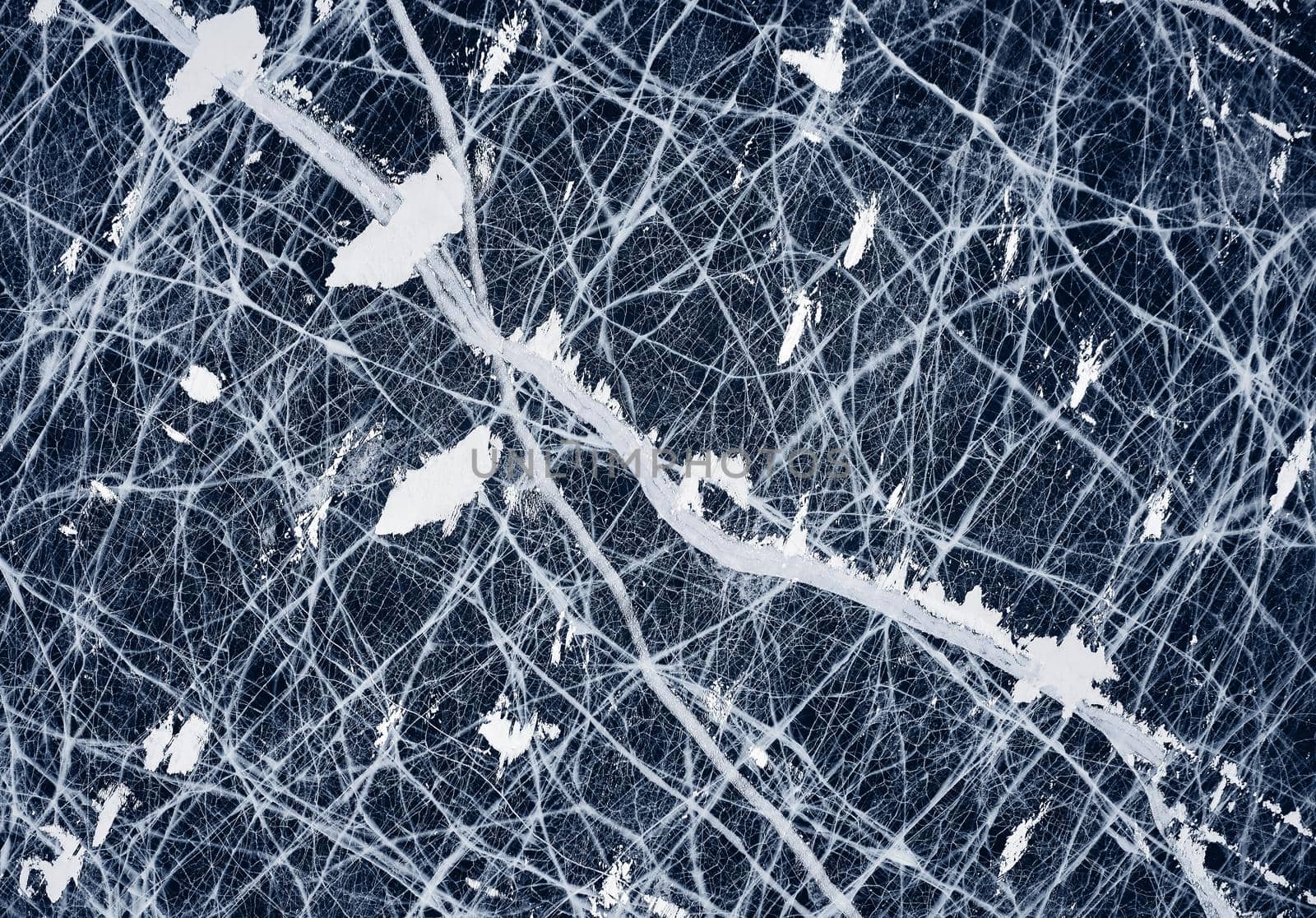 Deep blue ice - aerial view. Aesthetics of cracked ice. Frozen lake, texture of the ice. View of beautiful drawings on ice, Baikal lake in winter