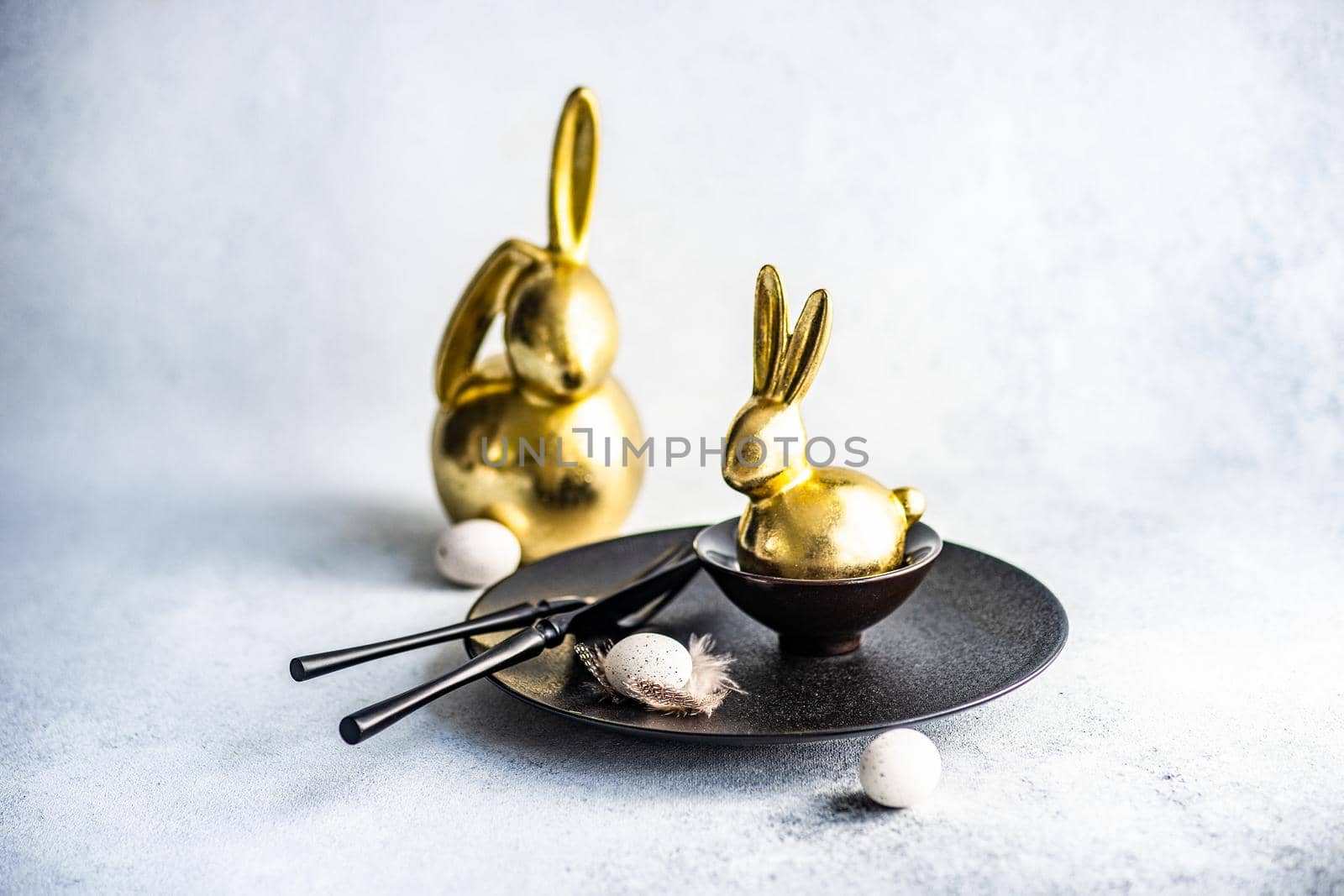 Festive table setting for Easter dinner on concrete background with black cutlery