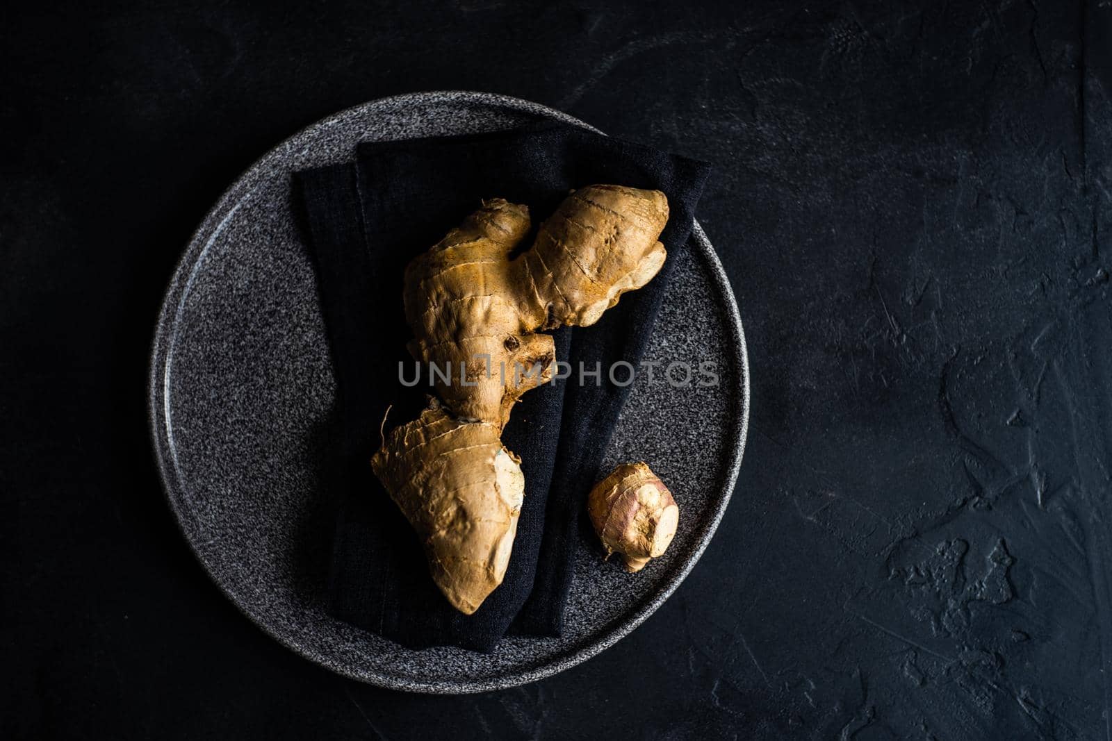 Organic food concept with raw ginger root on stoneware plate