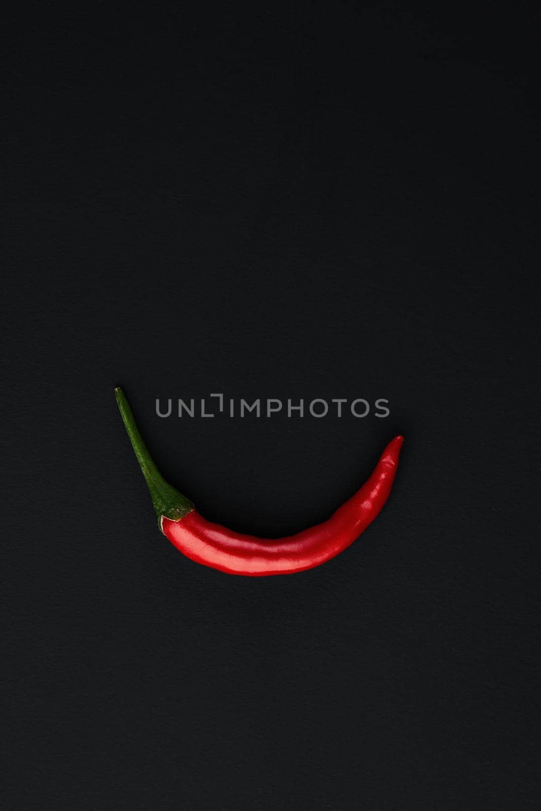 Red hot chili pepper on black background. Seasoning for real men. Fire seasoning.