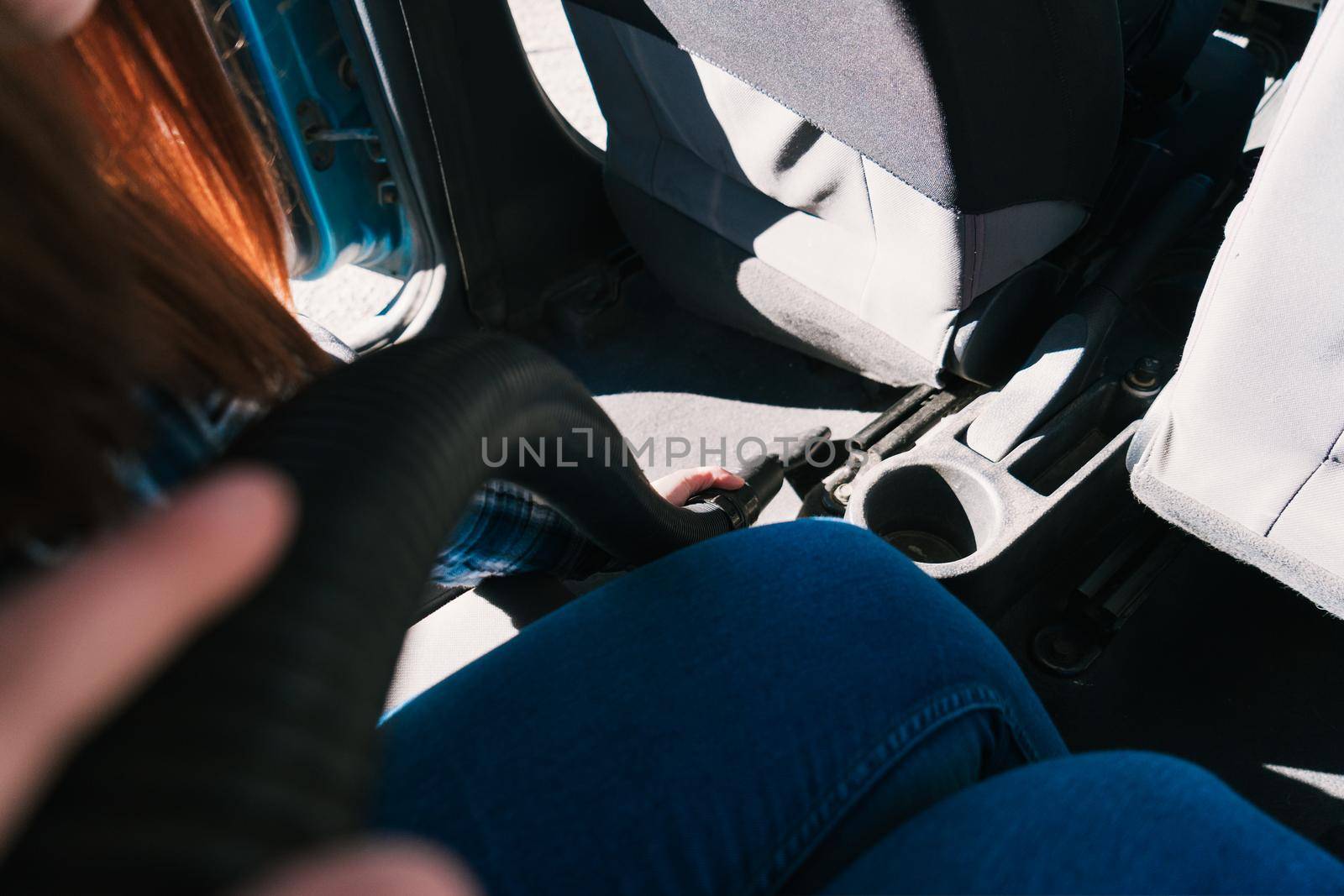 inside the car while a young woman cleans with a hoover. by CatPhotography