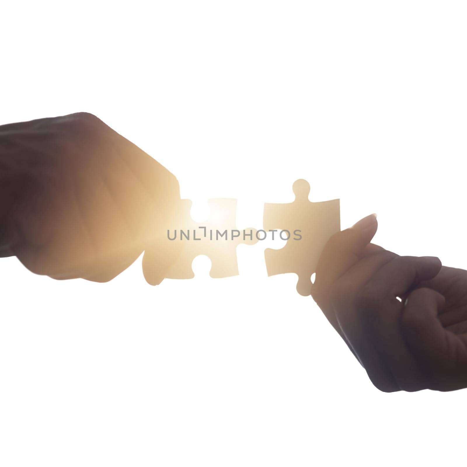 Closeup shot of two unrecognisable people putting two puzzle pieces together.