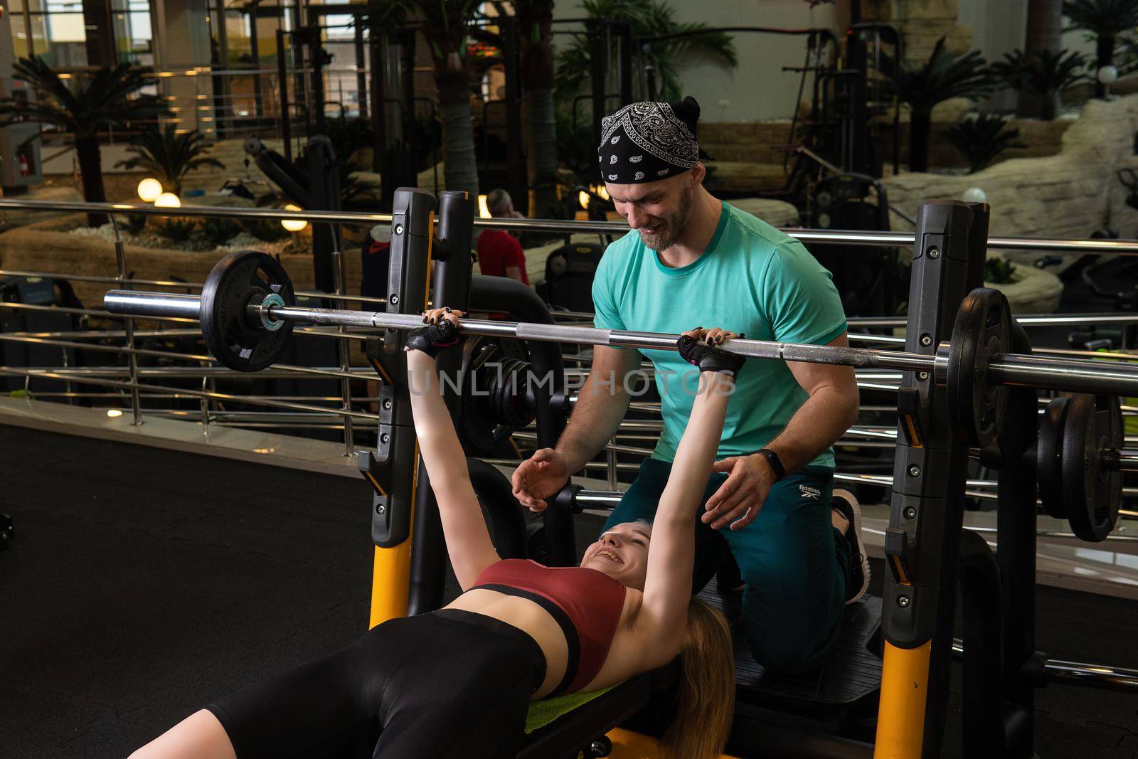 Instructor led training helps a beautiful client to perform exercises in a fitness club, the concept of playing sports with a professional gym leisure lifestyle men occupation, from professional senior for weightlifting from healthy instructor, sport helping. Fitness gymnasium elderly,
