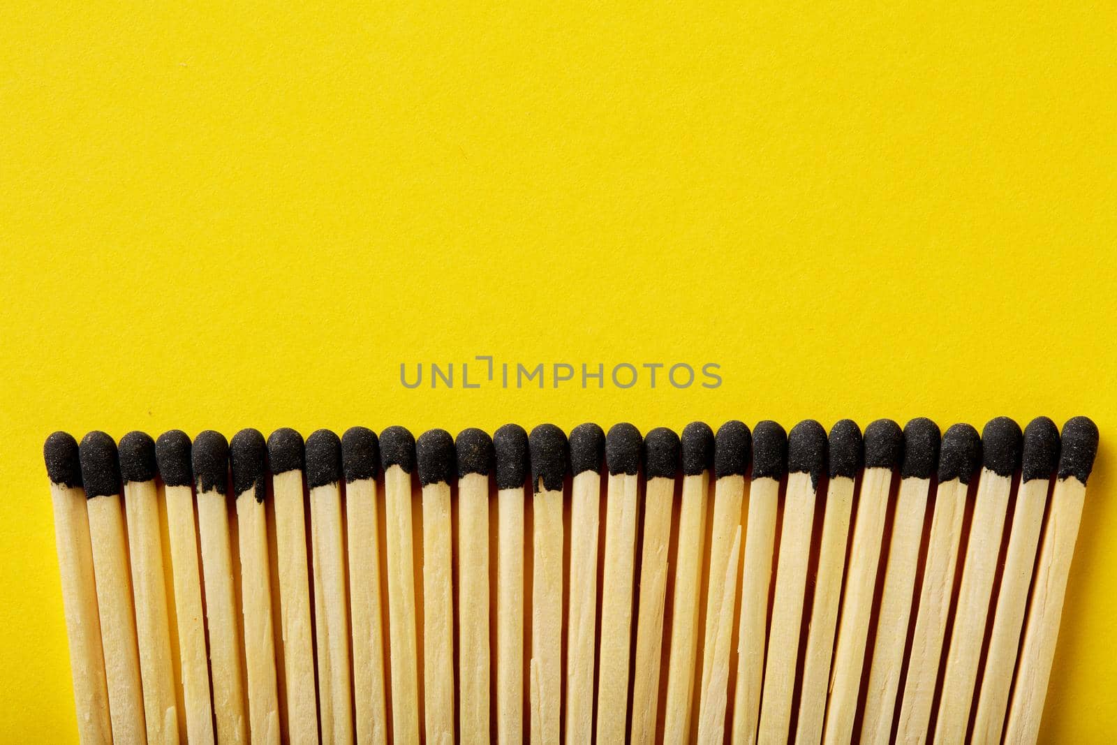 Matches on a yellow background, an abstraction about teamwork and modern relationships.