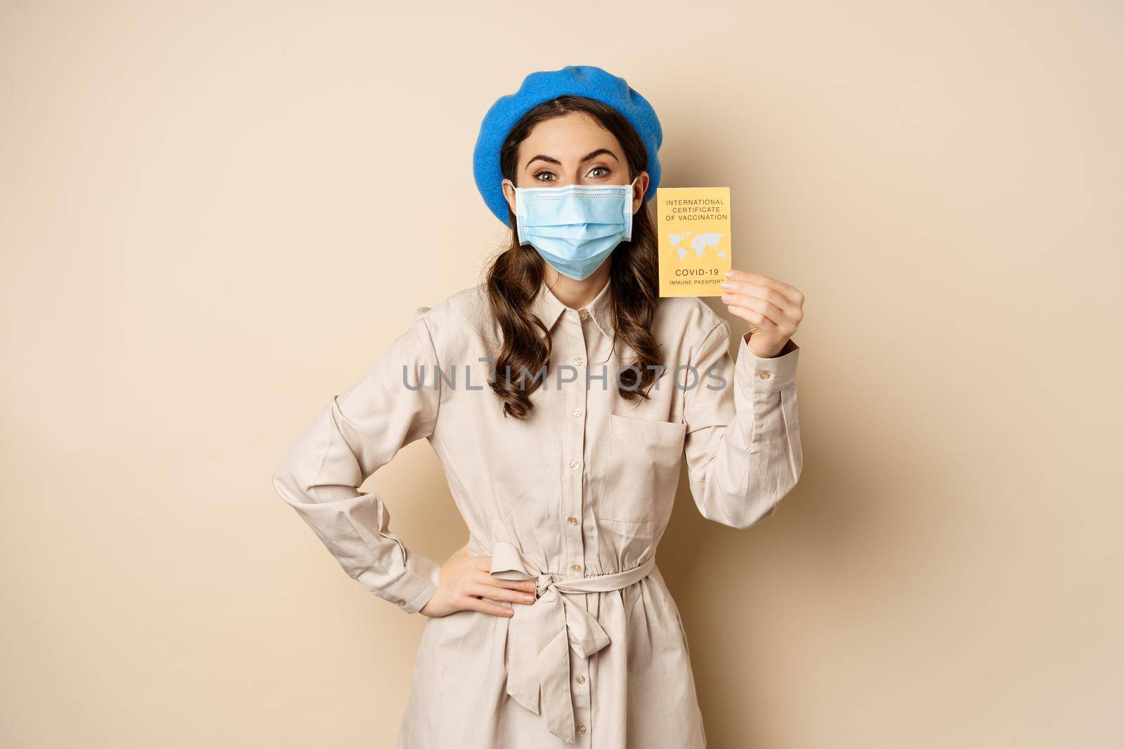 Covid pandemic and travelling concept. Girl tourist in medical face mask, travel vaccinated, showing international vaccination passport during coronavirus outbreak.