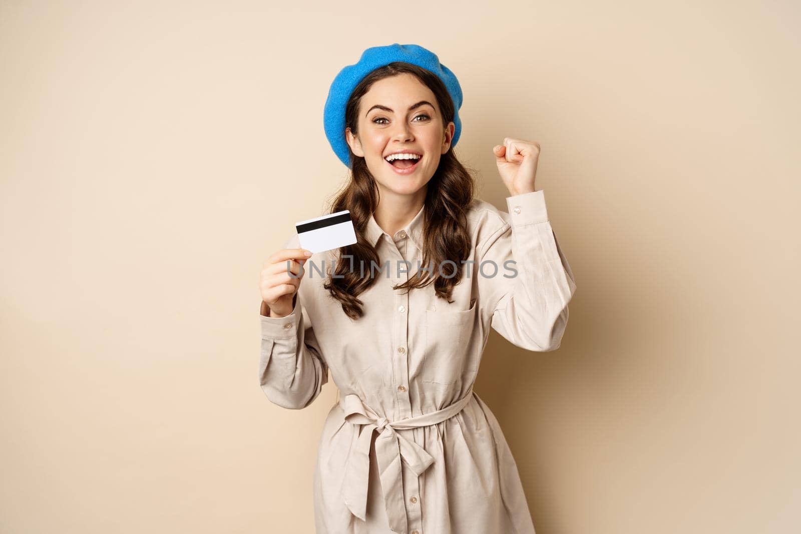 Enthusiastic young woman yearning to go shopping, dancing with credit card and celebrating, laughing and smiling.