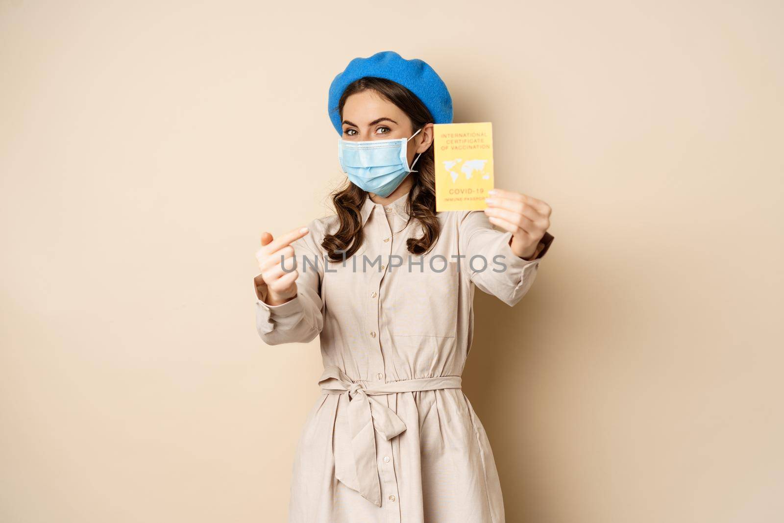 Covid pandemic and travelling concept. Girl tourist in medical face mask, travel vaccinated, showing international vaccination passport during coronavirus outbreak.