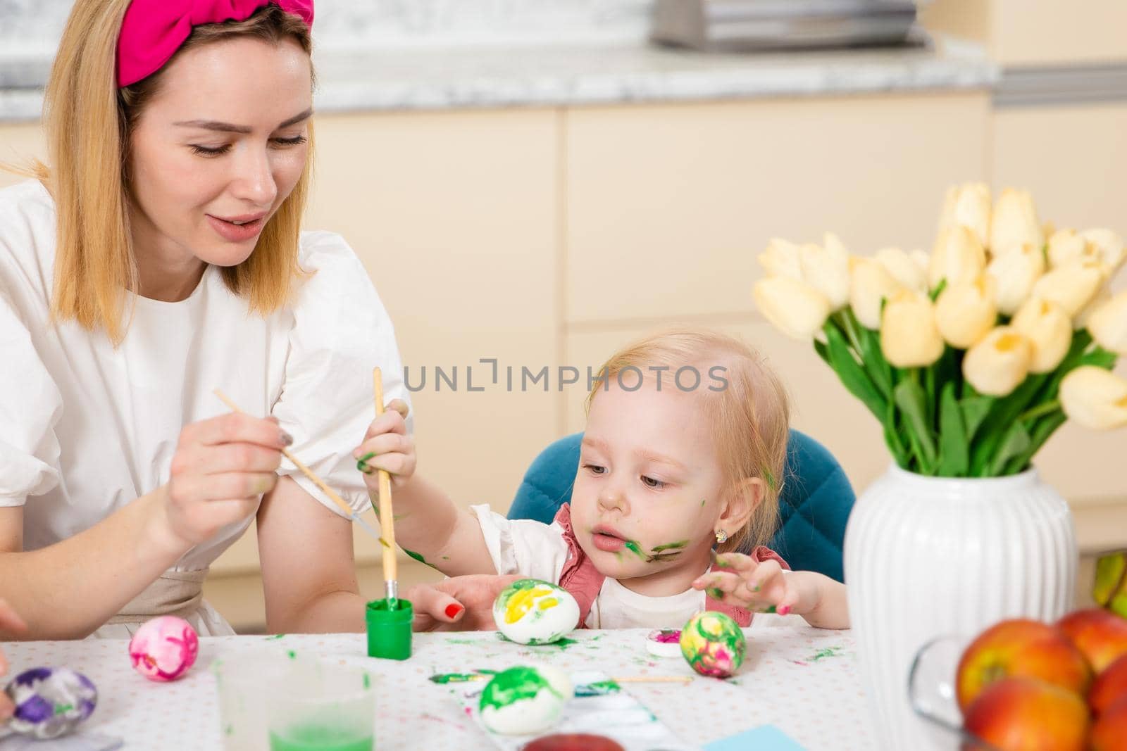 Happy Family preparing for Easter. Cute girl with mother painting eggs. Home activity. Concept of unity and love. Mom and daughter by Marina-A