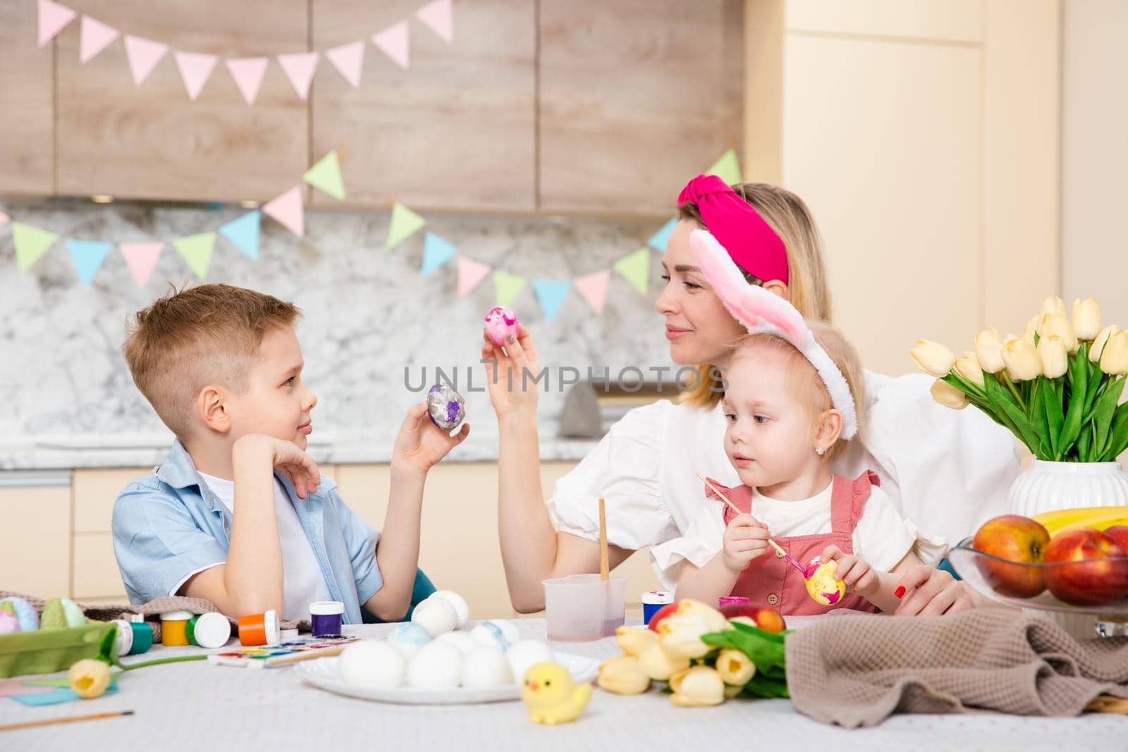 Big Happy Family preparing for Easter. Cute children with mother painting eggs. Home activity. Concept of unity and love. Mom, son, daughter. Brother and sister