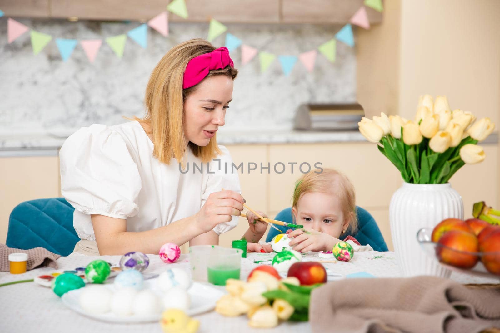 Big Happy Family preparing for Easter. Cute girl with mother painting eggs. Home activity. Concept of unity and love. Mom and daughter