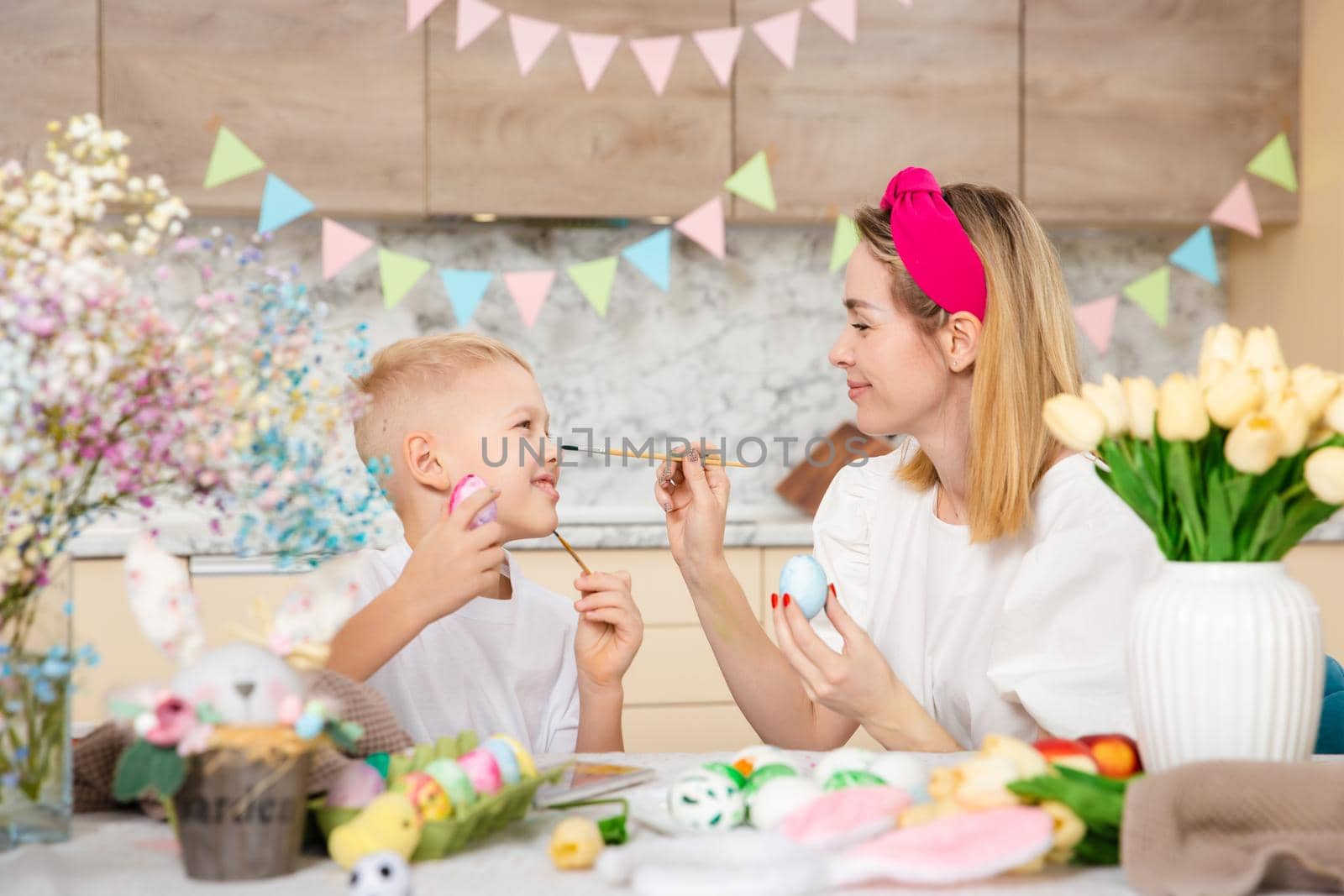 Happy Family preparing for Easter. Cute child with mother painting eggs. Home activity. Concept of unity and love. Mom and son. by Marina-A