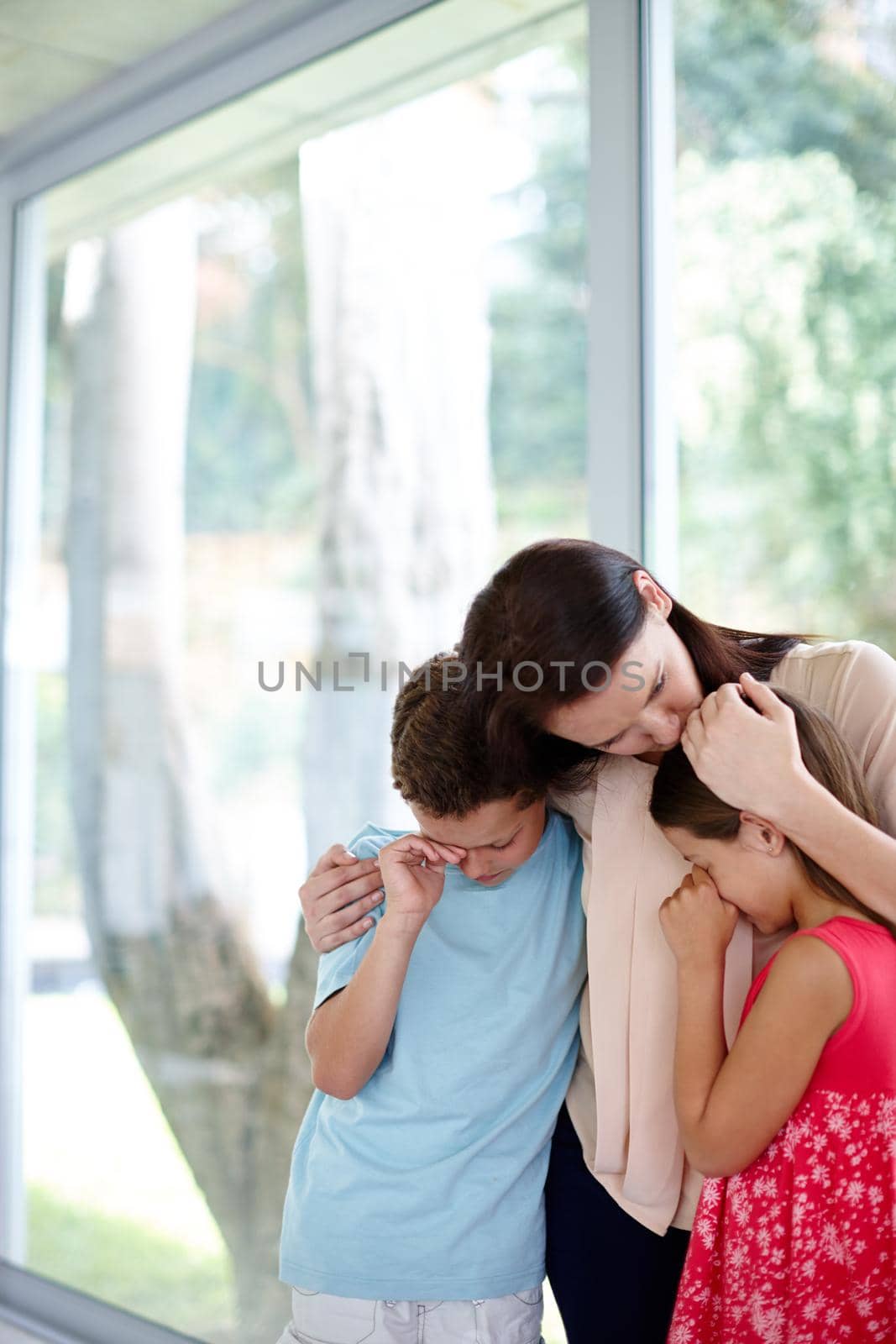 Grieving as a family. Shot of a family supporting each other in their grief. by YuriArcurs