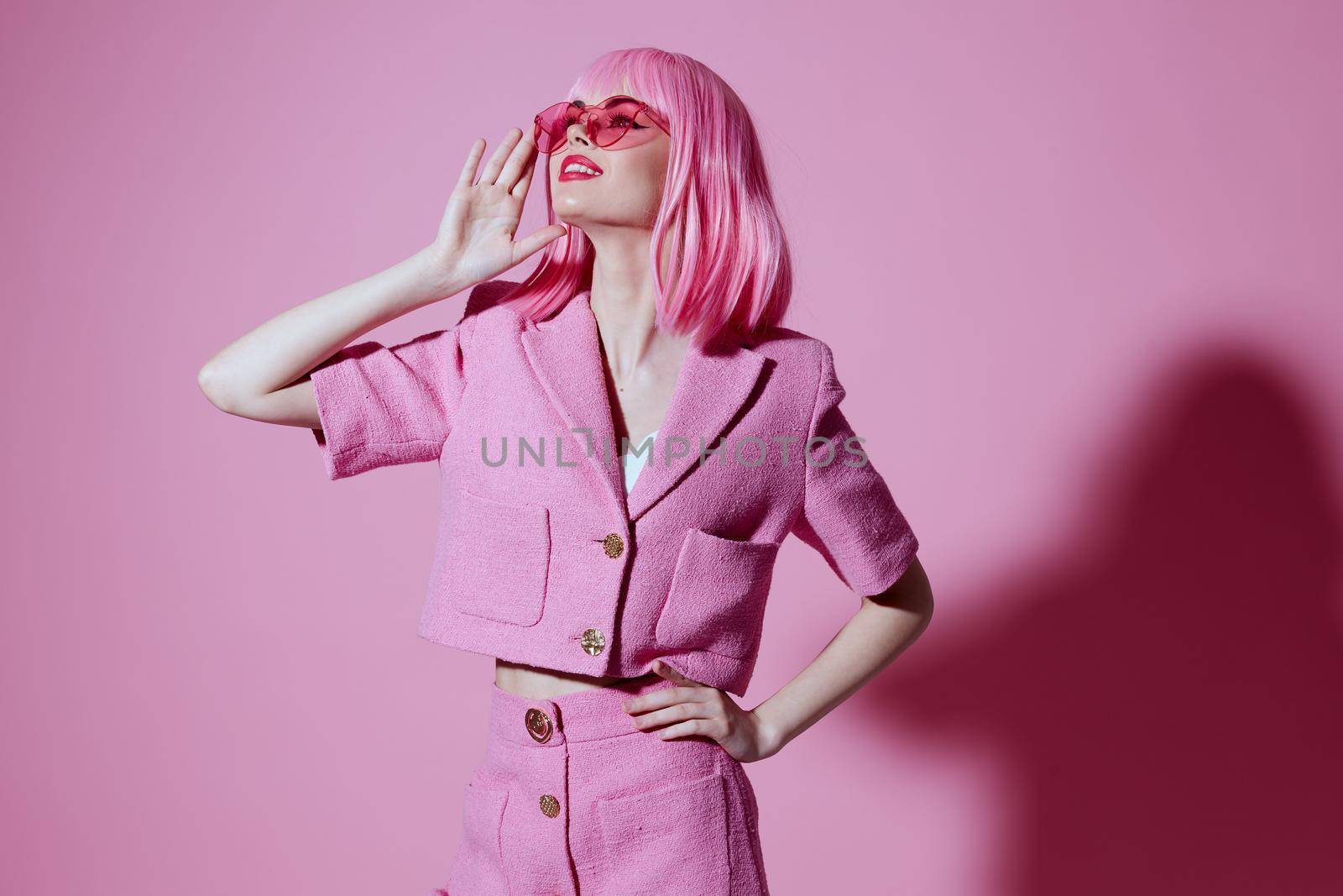 Pretty young female gestures with his hands with a pink jacket pink background unaltered. High quality photo