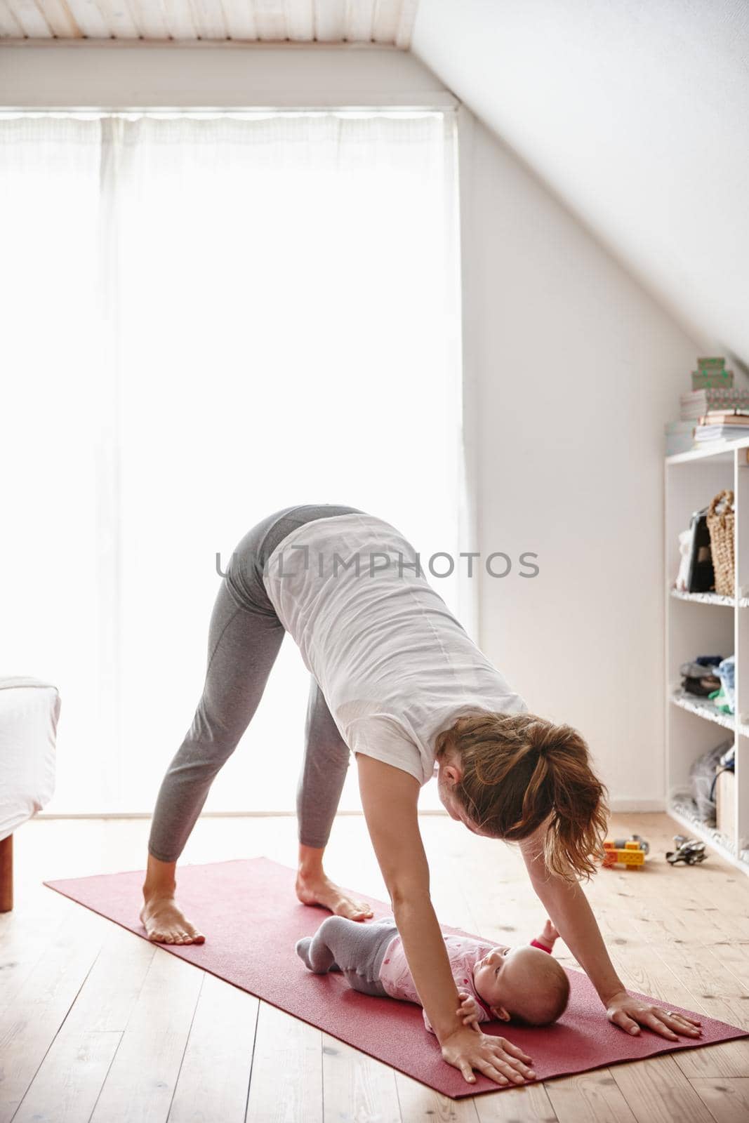 Peek-a-boo. Shot of an attractive young woman bonding with her baby girl while doing yoga. by YuriArcurs