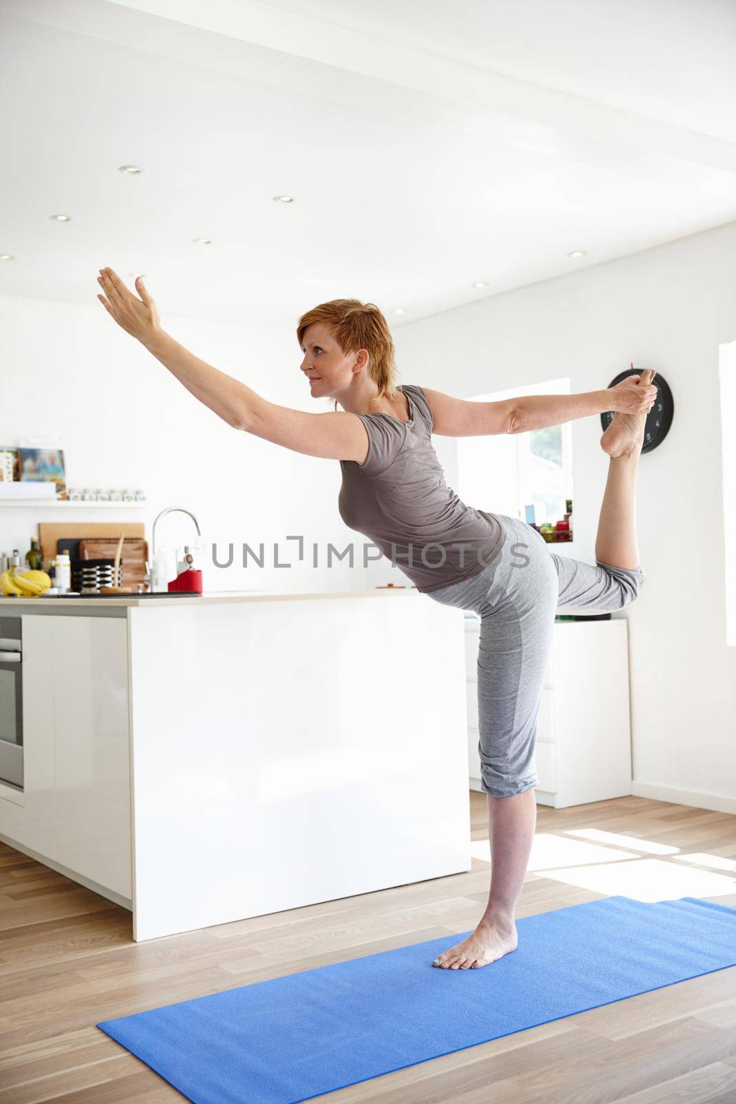 Stretching towards wellness. Shot of an attractive woman doing yoga in her home. by YuriArcurs