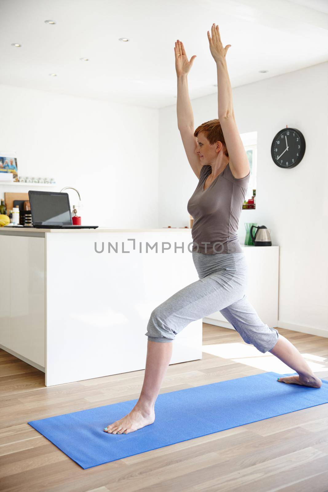 Domestic warrior. Shot of an attractive woman doing yoga in her home. by YuriArcurs