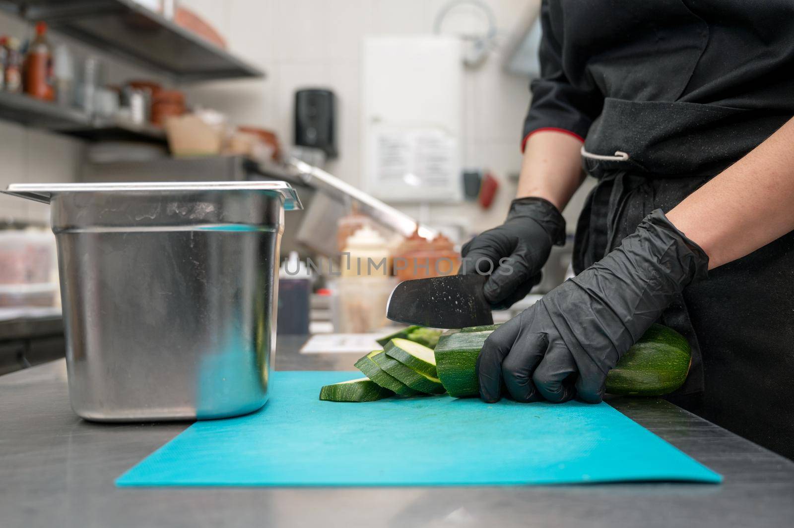 Female chef cutting vegetables at a commercial kitchen. by HERRAEZ
