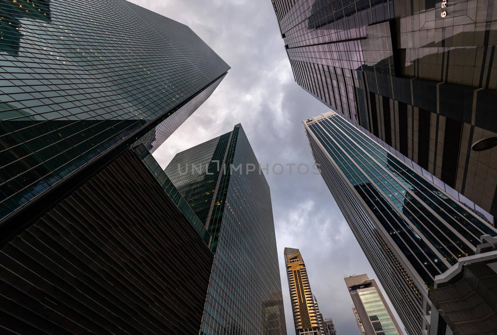 Glass Facades of skyscrapers of the financial district of Singapore on a cloudy evening, bottom view, wide lens, city center, building of large companies without logos. High quality photo