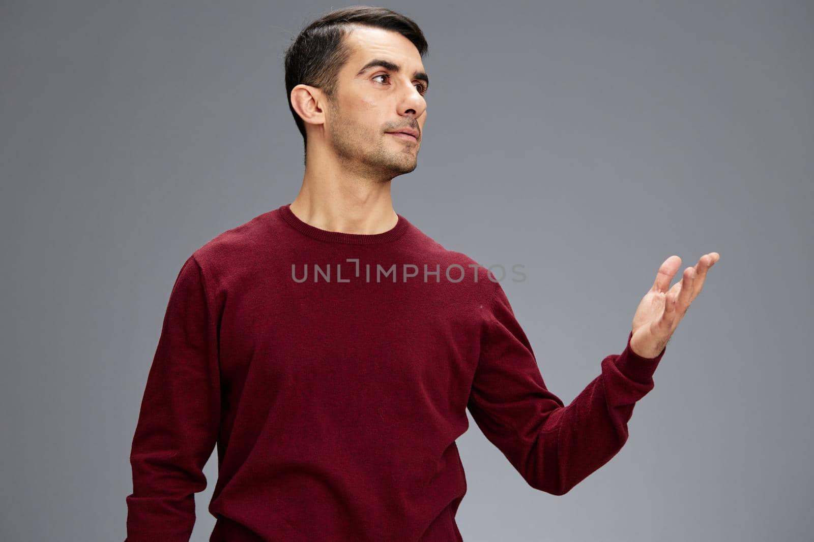 manager in a red sweater gesturing with hands posing Gray background. High quality photo