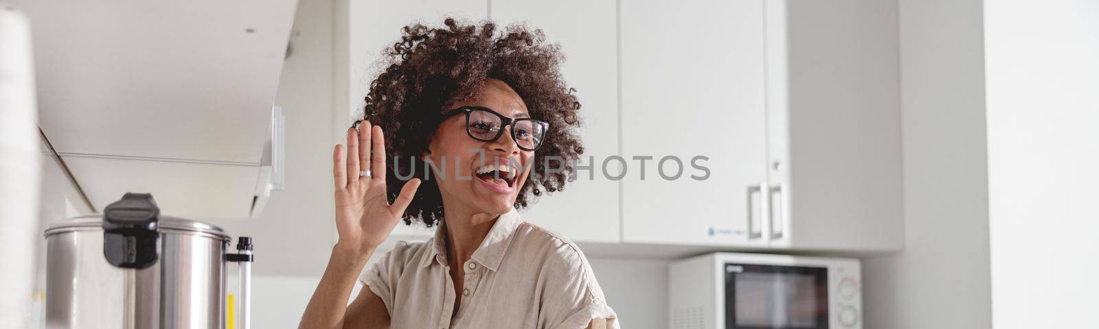Happy Afro American lady waving to colleague and preparing hot drink on office kitchen