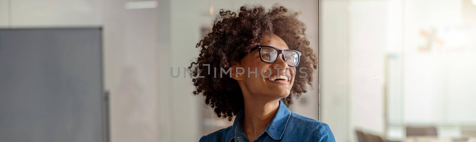 Smiling African American lady holding a notebook with documents with two hands in meeting room