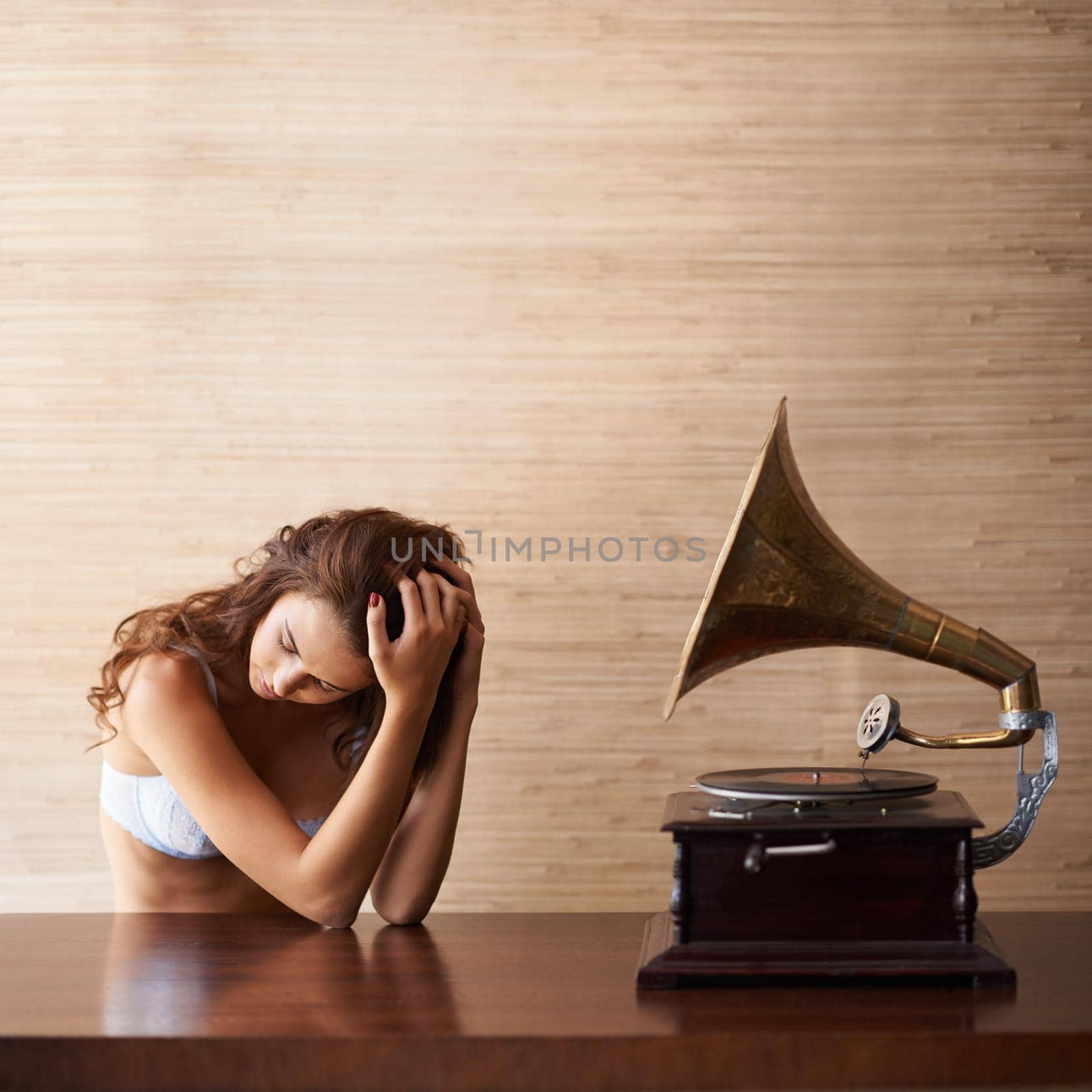 An attractive young woman in lacy lingerie sitting beside a gramophone.