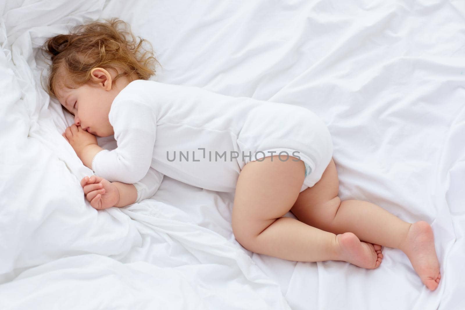An adorable baby sleeping on the bed.