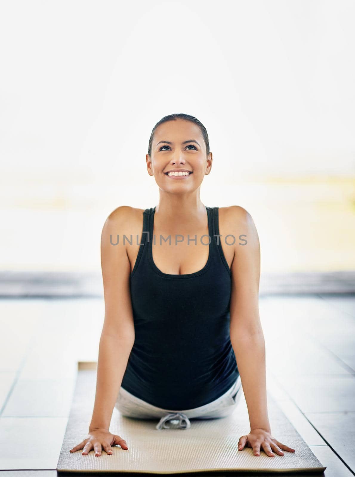 Release those endorphins. Shot of a young woman doing yoga at home. by YuriArcurs