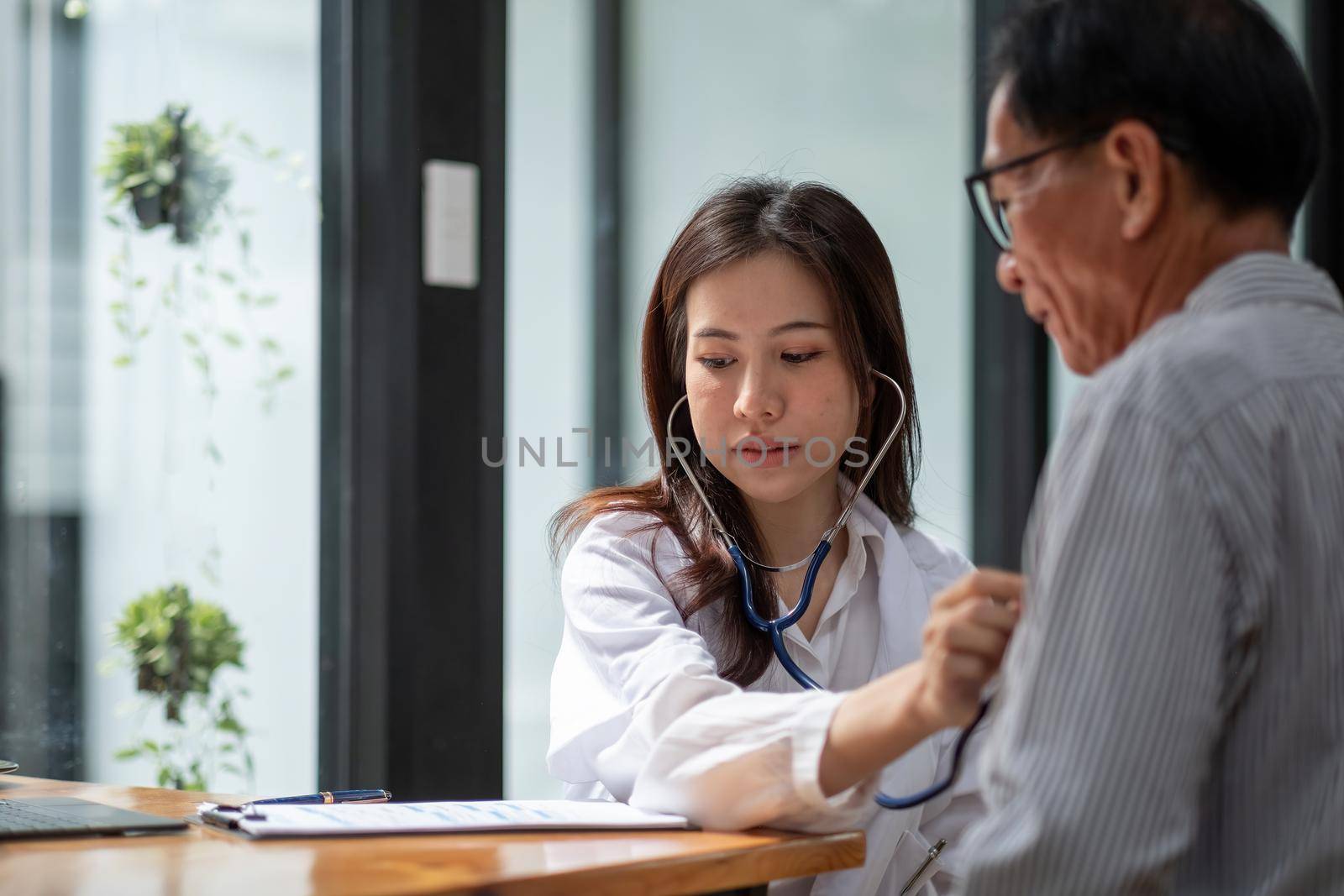 Stethoscope exam. Attractive cheerful asian female doctor listening to the elderly while using stethoscope.