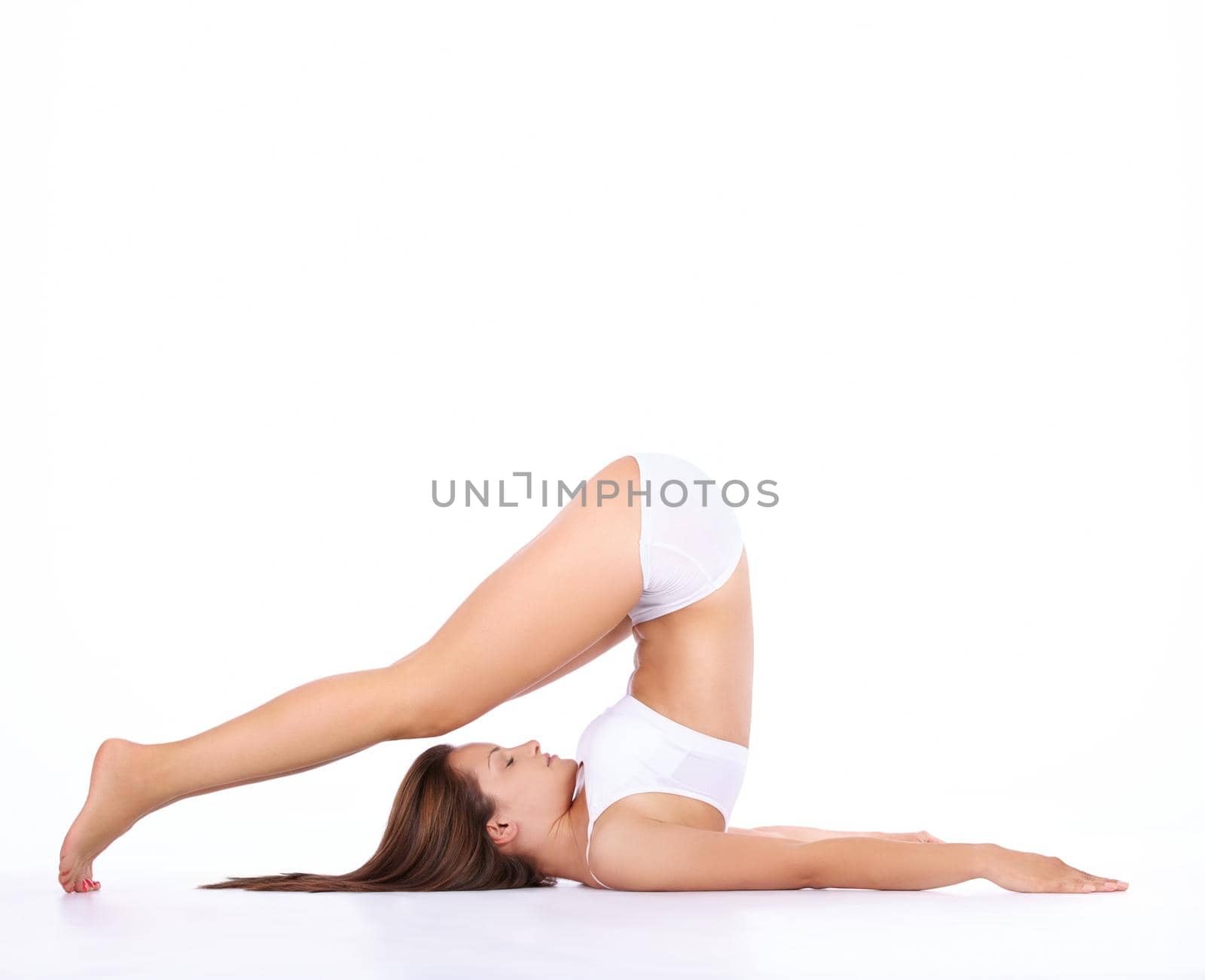 Studio shot of a young woman in underwear stretching isolated on white.