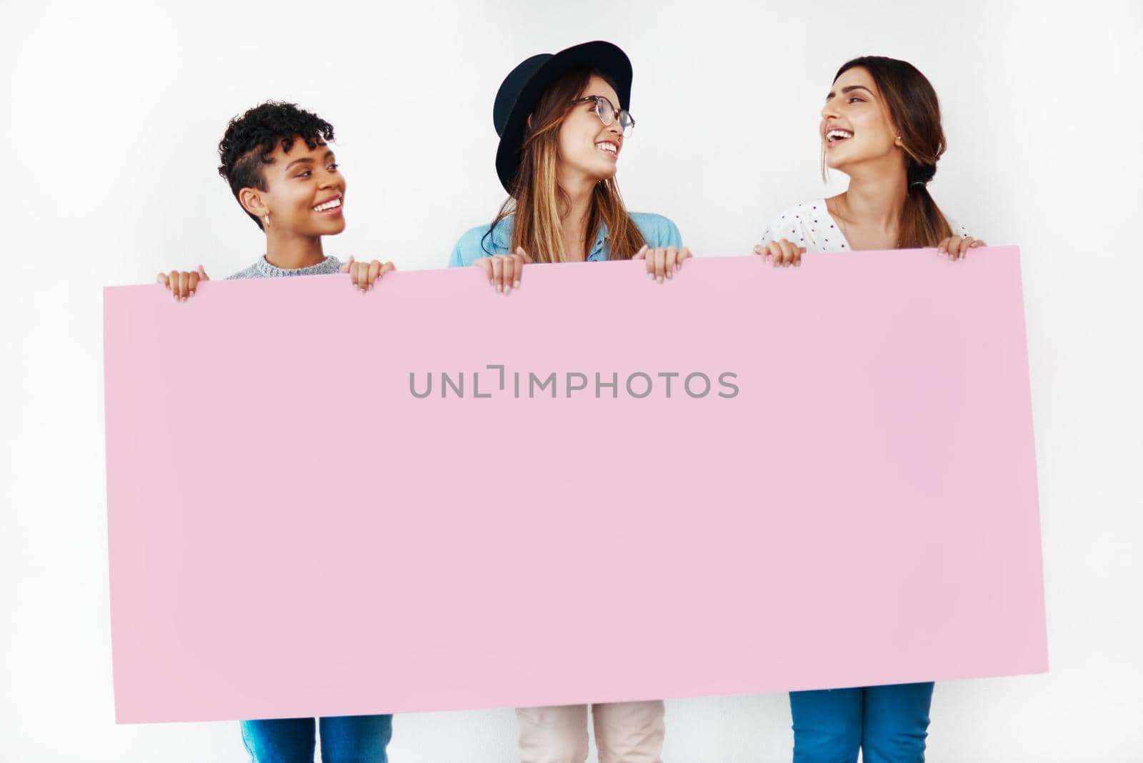 Studio shot of a group of young women holding a blank placard against a white background.