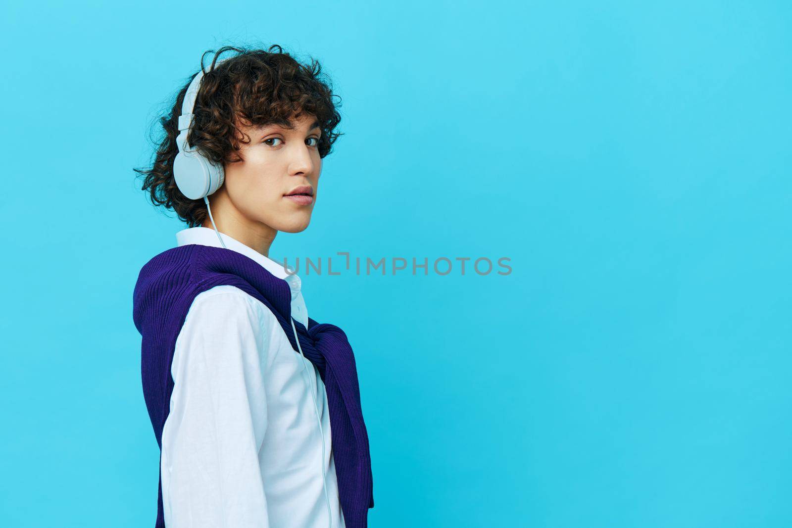 teenager in headphones listening to music blue background by SHOTPRIME