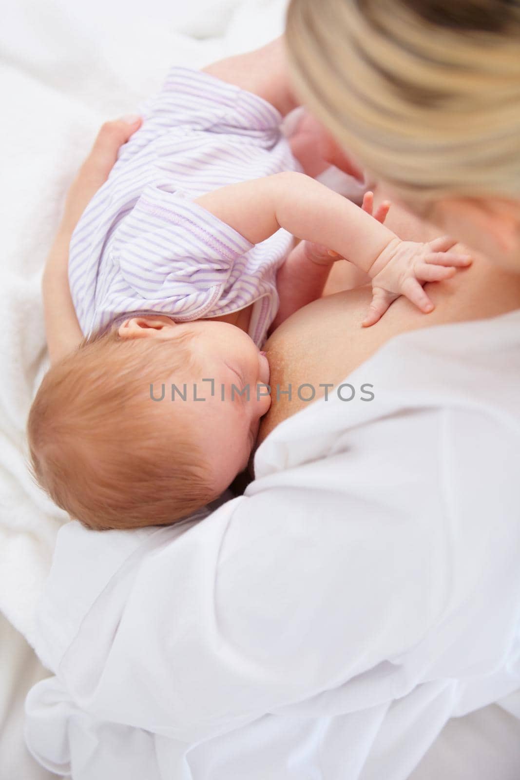 Portrait of motherhood. High angle shot of a mother breastfeeding her newborn baby. by YuriArcurs