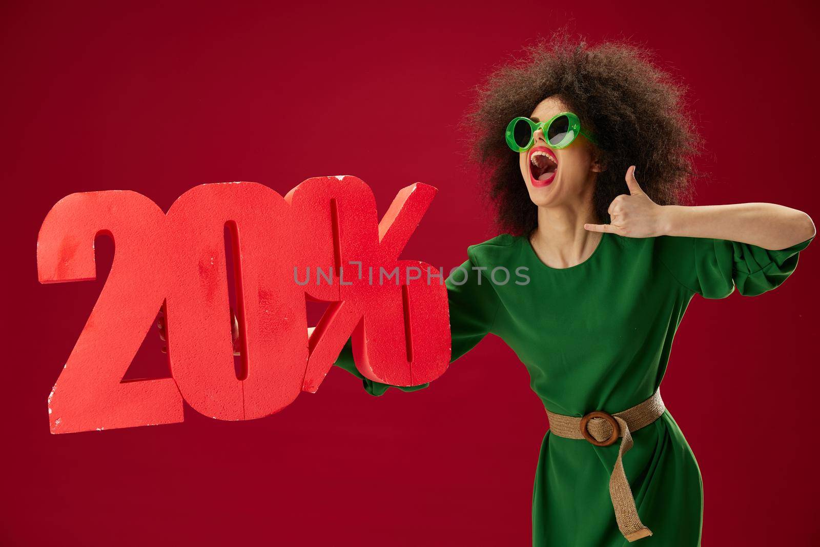 Portrait of a charming lady curly hairstyles green dress twenty percent discount red background unaltered. High quality photo