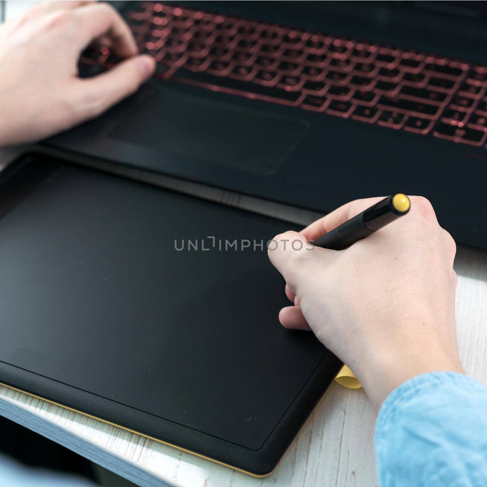 designer working on a professional tablet with a pen, Close-up of a man's hand holding a graphic pen for drawing