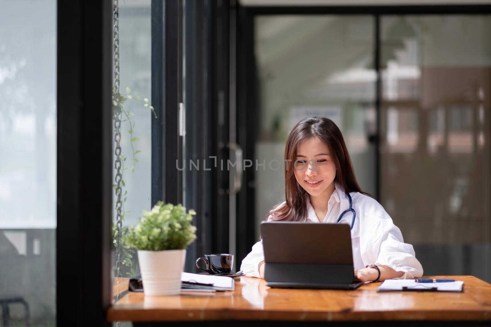 Portrait happy asian woman doctor in hospital, female using smart digital tablet