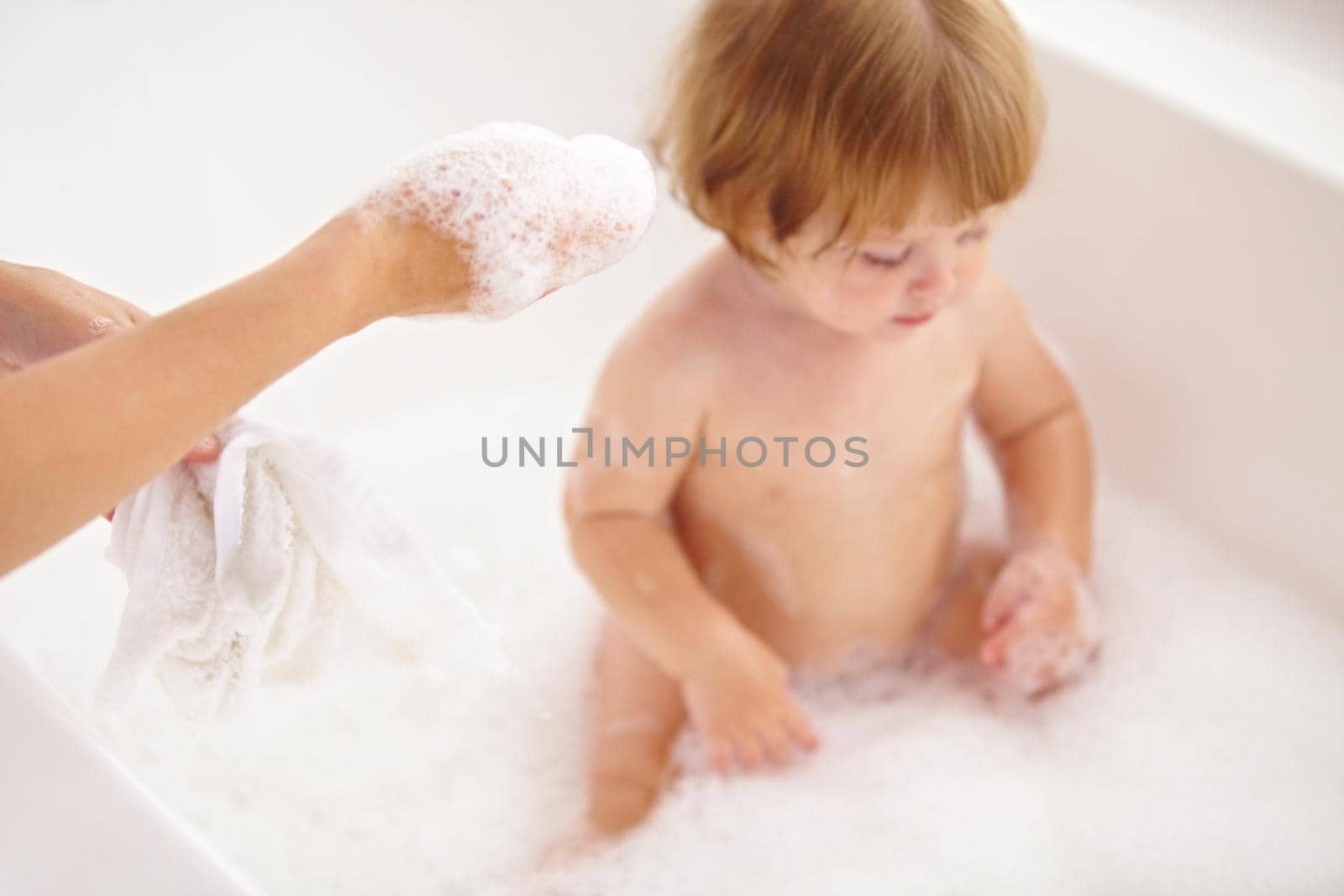 Even baby loves a bubble bath. Cropped shot of a baby girl being bathed by her mother. by YuriArcurs