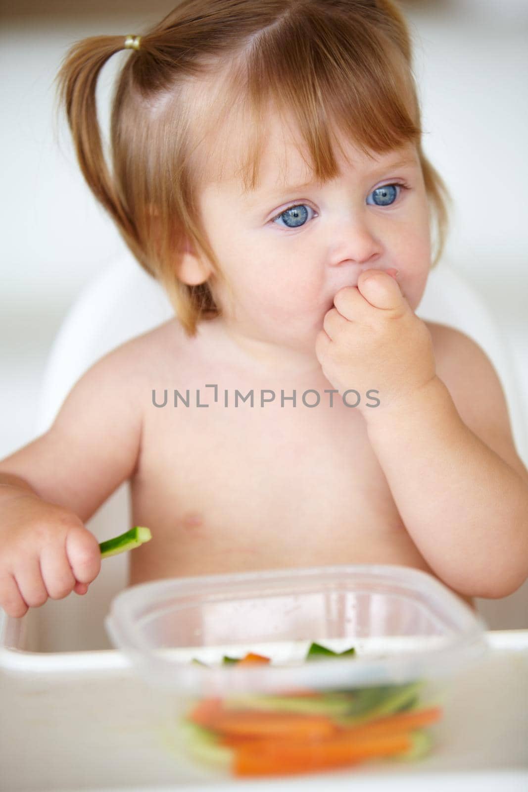 A cute little girl eating vegetables.