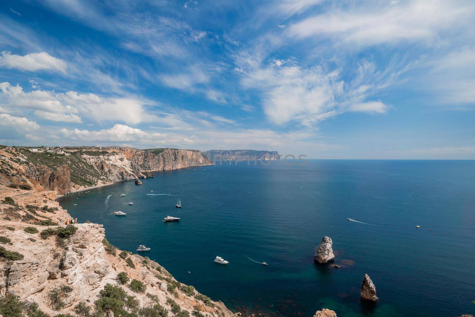 Two rocks stick out of the water in the middle of the turquoise sea. Scenic ocean view. Speed boat sails on the sea. High quality photo.