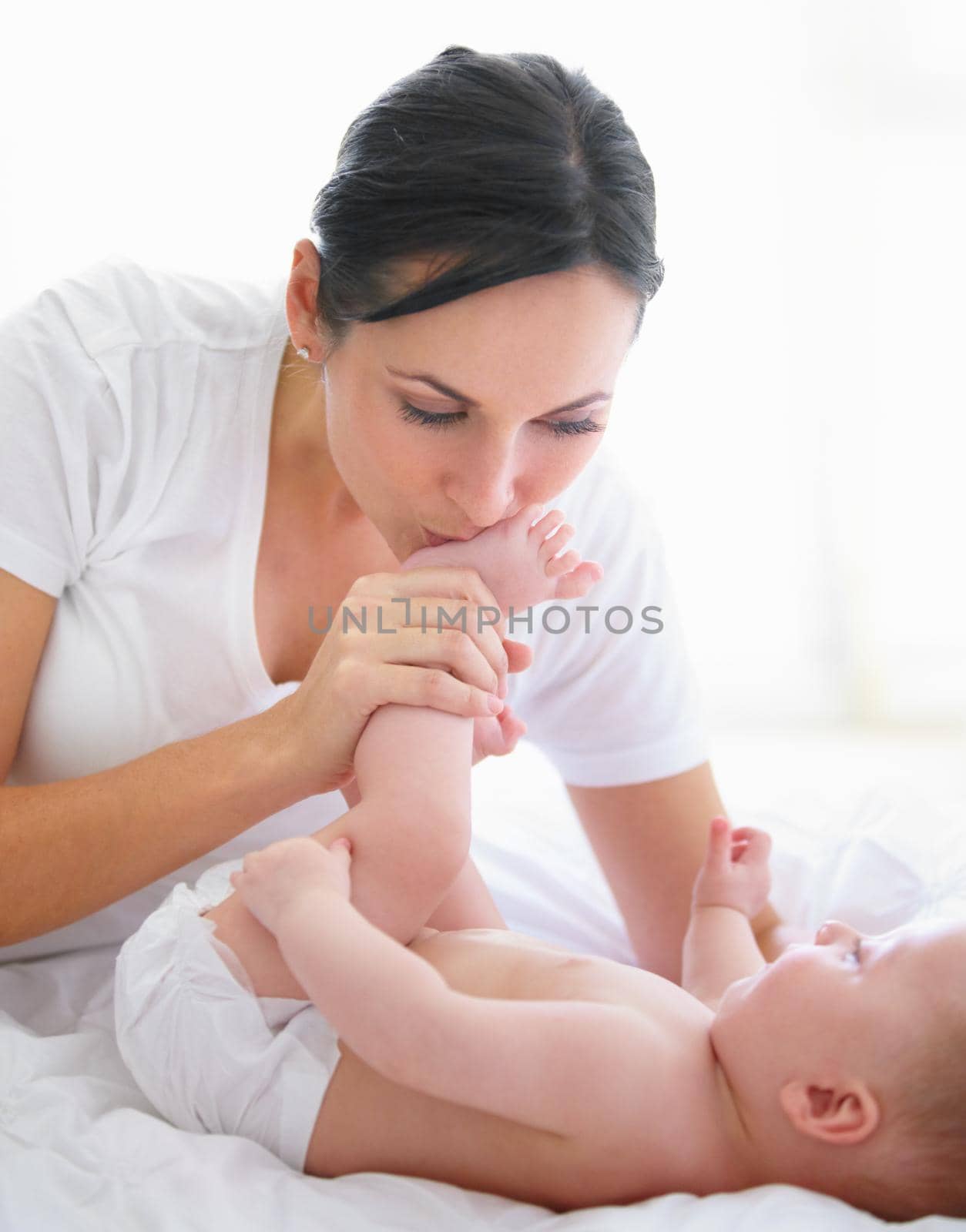 Beautiful woman kissing her babys feet.